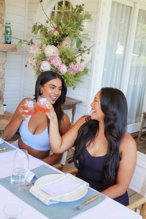 Two woman clinking glasses together